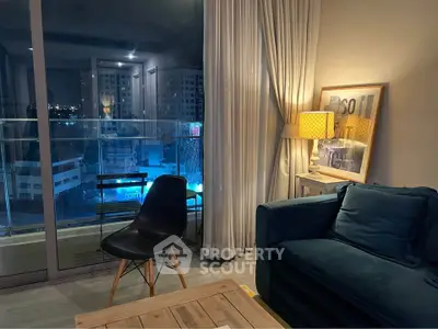 Cozy living room with modern furniture and city view from balcony at night.