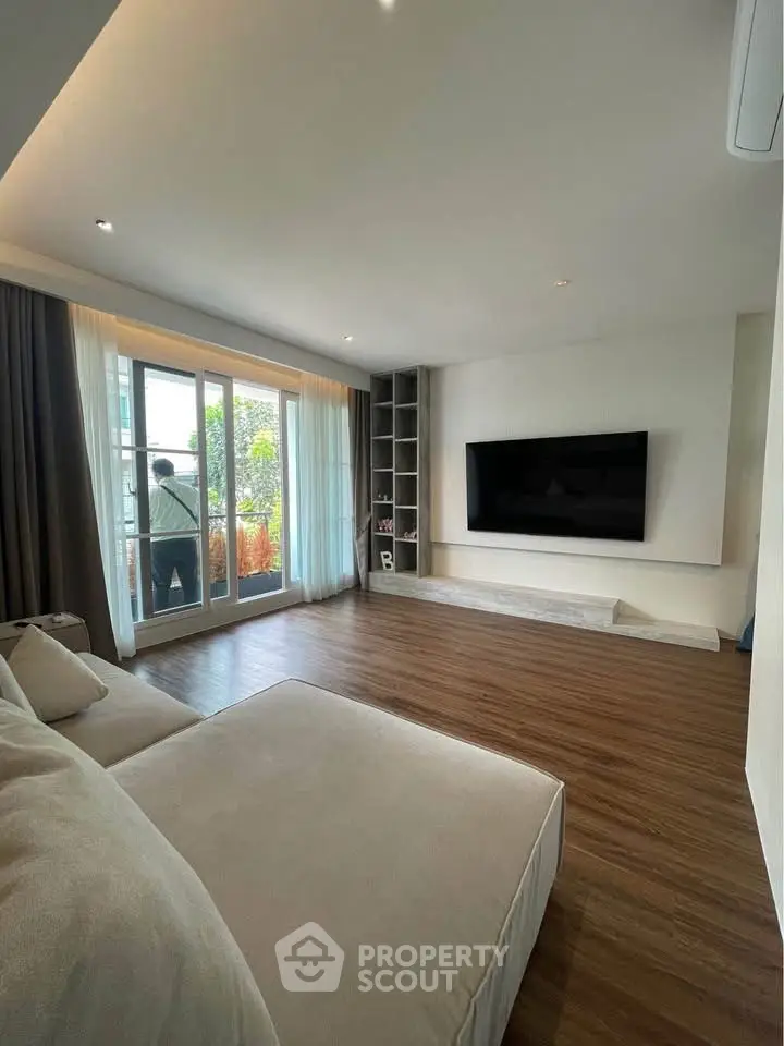 Spacious modern living room with large window and sleek TV setup