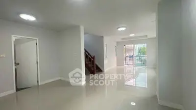 Spacious open-plan living area with glossy tiled floors and natural light.