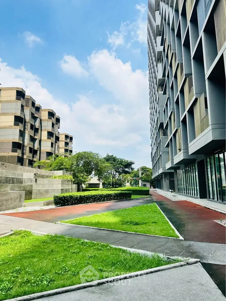 Modern apartment building with lush green landscaping and clear blue sky.