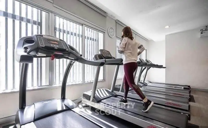 Modern gym with multiple treadmills and large windows for natural light.