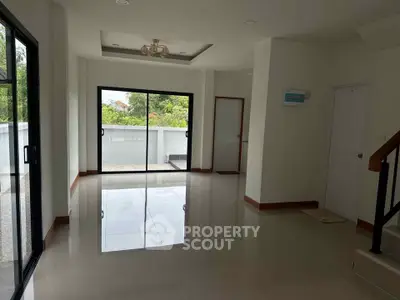Spacious modern living room with large windows and glossy tile flooring, offering ample natural light and garden view.