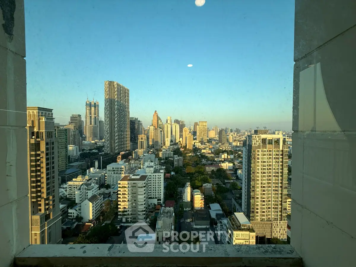 Stunning cityscape view from high-rise window showcasing urban skyline at sunset.