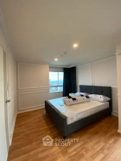 Spacious bedroom with modern decor and large window offering city views.