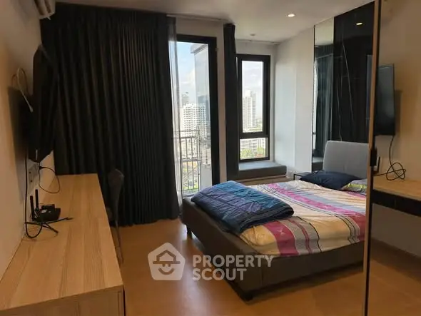 Modern bedroom with city view, featuring sleek furniture and large windows for natural light.