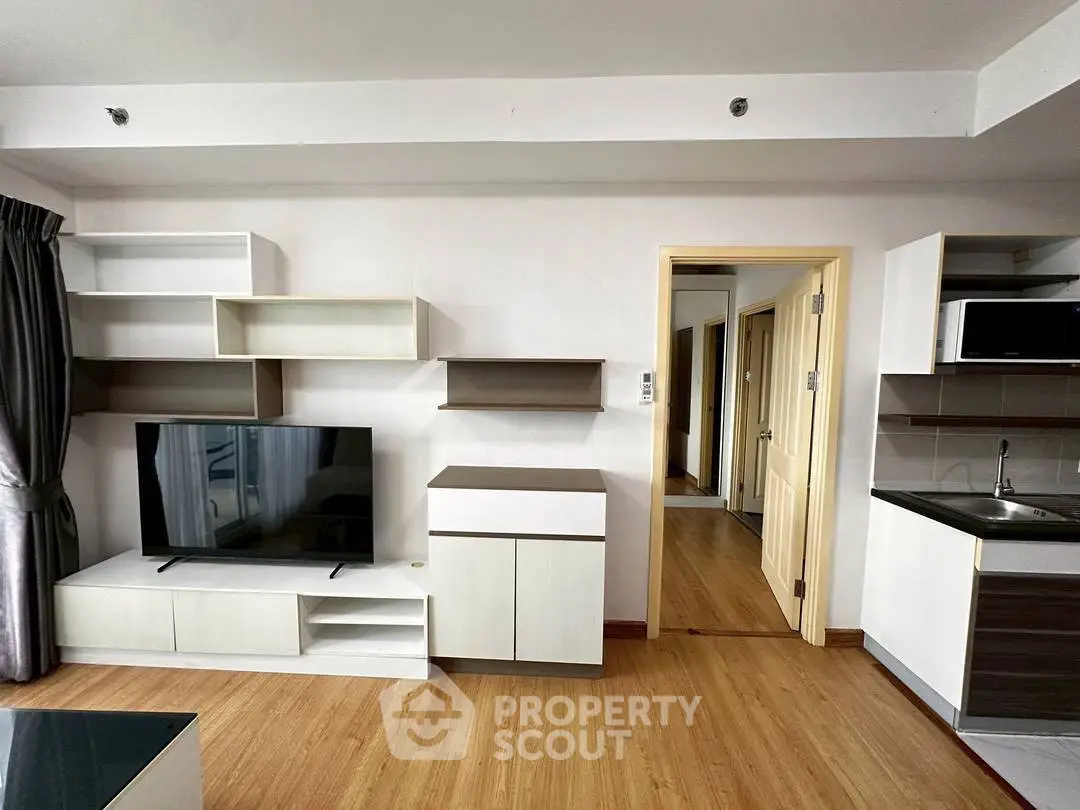 Modern living room with sleek TV unit and open kitchen layout in stylish apartment.