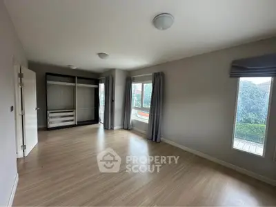 Spacious empty bedroom with large windows and built-in wardrobe