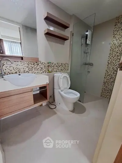 Modern bathroom with sleek fixtures and glass shower enclosure in contemporary apartment.
