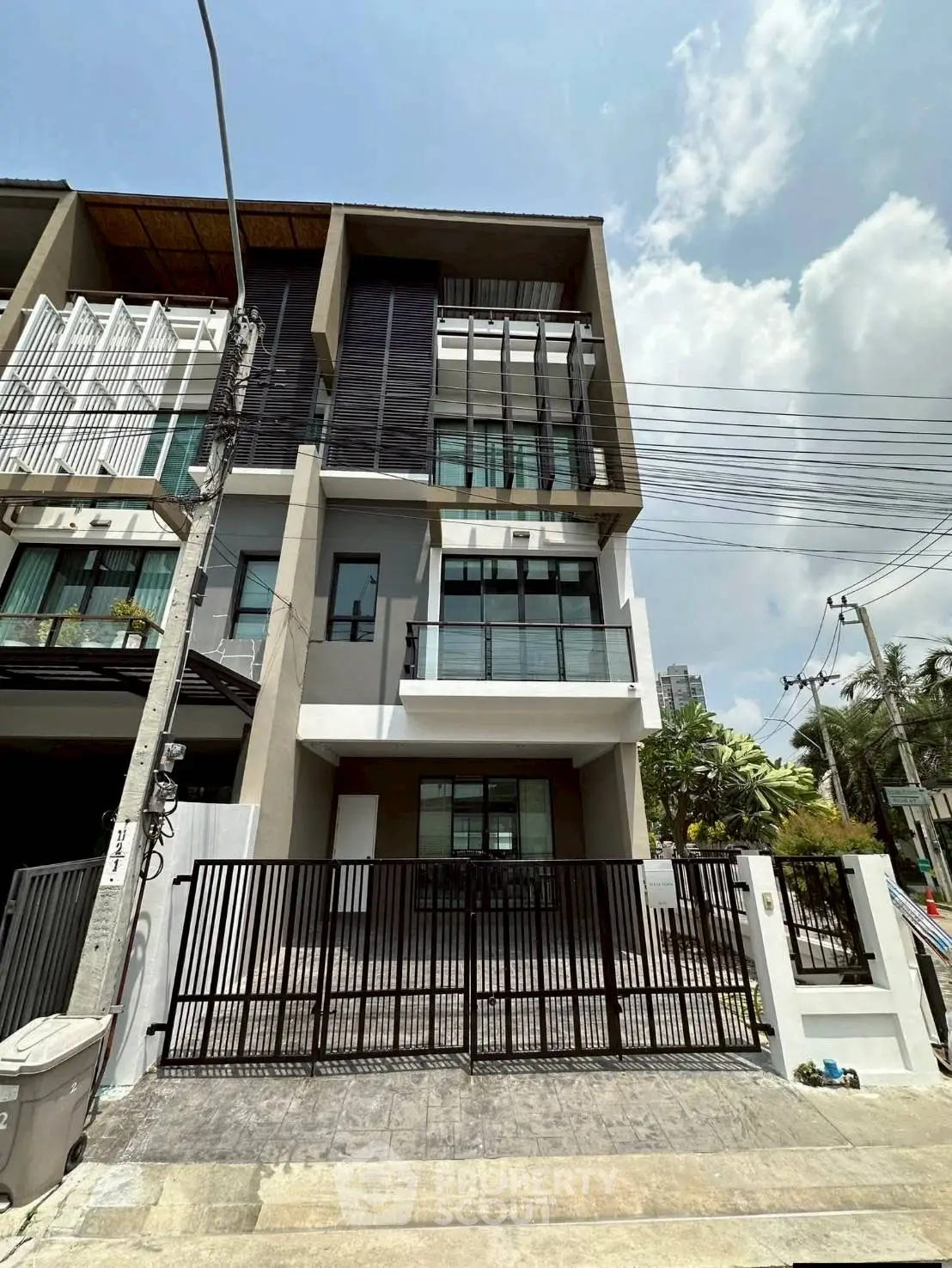 Modern multi-story townhouse with sleek design and gated entrance in urban setting.