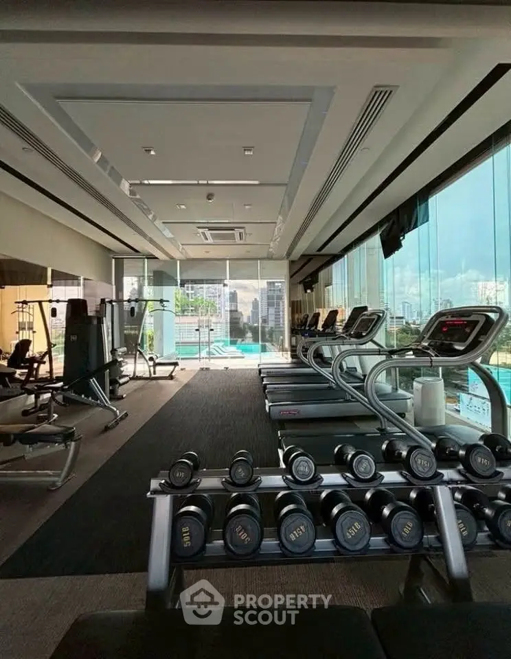 Modern gym with city view and state-of-the-art equipment in luxury building.