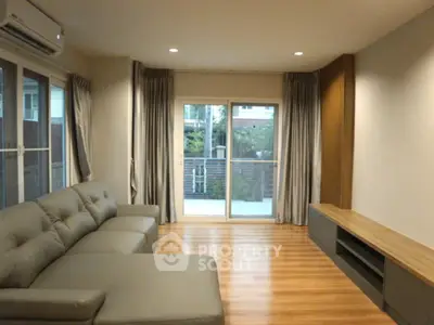 Spacious living room with modern sofa and large windows opening to a balcony.