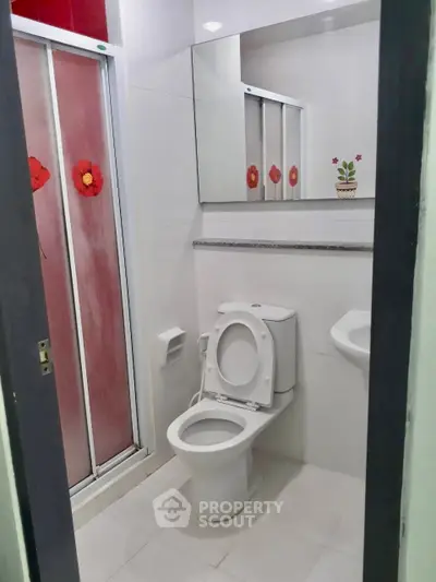 Modern bathroom with sleek design and floral accents, featuring a shower and toilet.