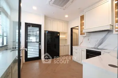 Modern kitchen with sleek cabinetry, marble countertops, and glass door entry.