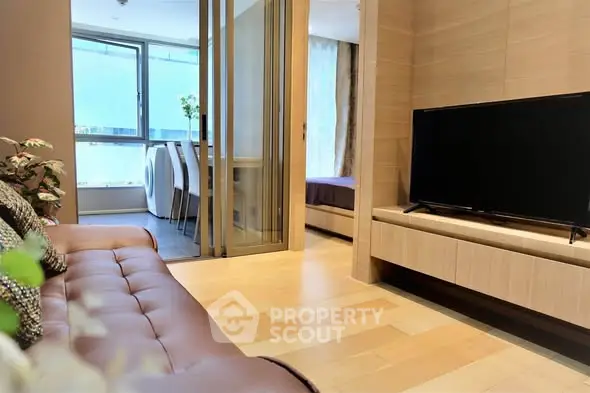 Modern living room with sleek design and natural light, featuring a cozy sofa and flat-screen TV.