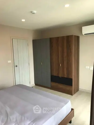 Modern bedroom with sleek wardrobe and air conditioning in a stylish apartment.