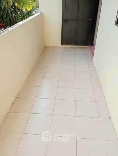 Spacious balcony with tiled flooring and secure door access, ideal for relaxation.