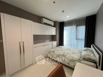 Modern bedroom with sleek white furniture and large window for natural light