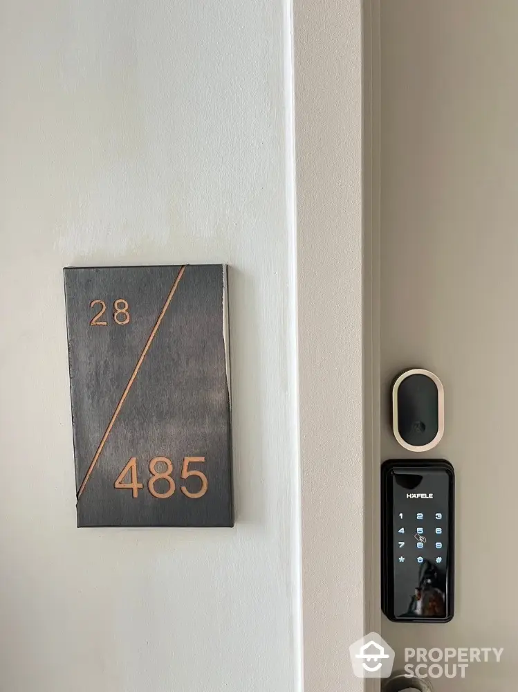 Modern apartment entrance with digital lock and stylish room number plaque.