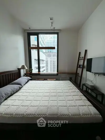 Modern bedroom with large window and city view, featuring minimalist decor and wall-mounted TV.