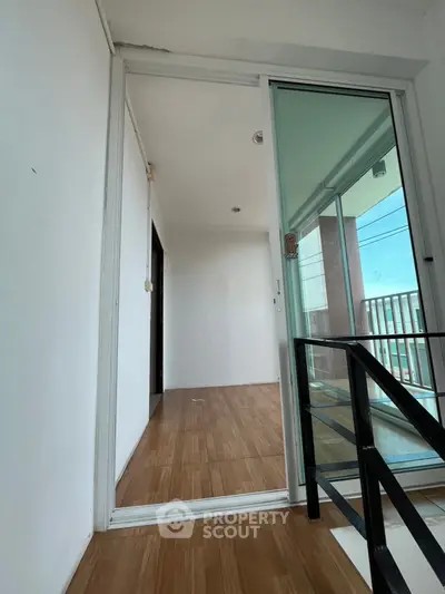 Modern apartment balcony with sliding glass door and wooden flooring