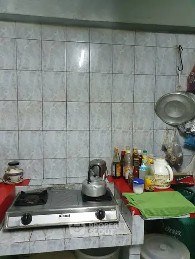 Compact kitchen with gas stove and tiled backsplash, featuring essential cooking condiments and utensils.