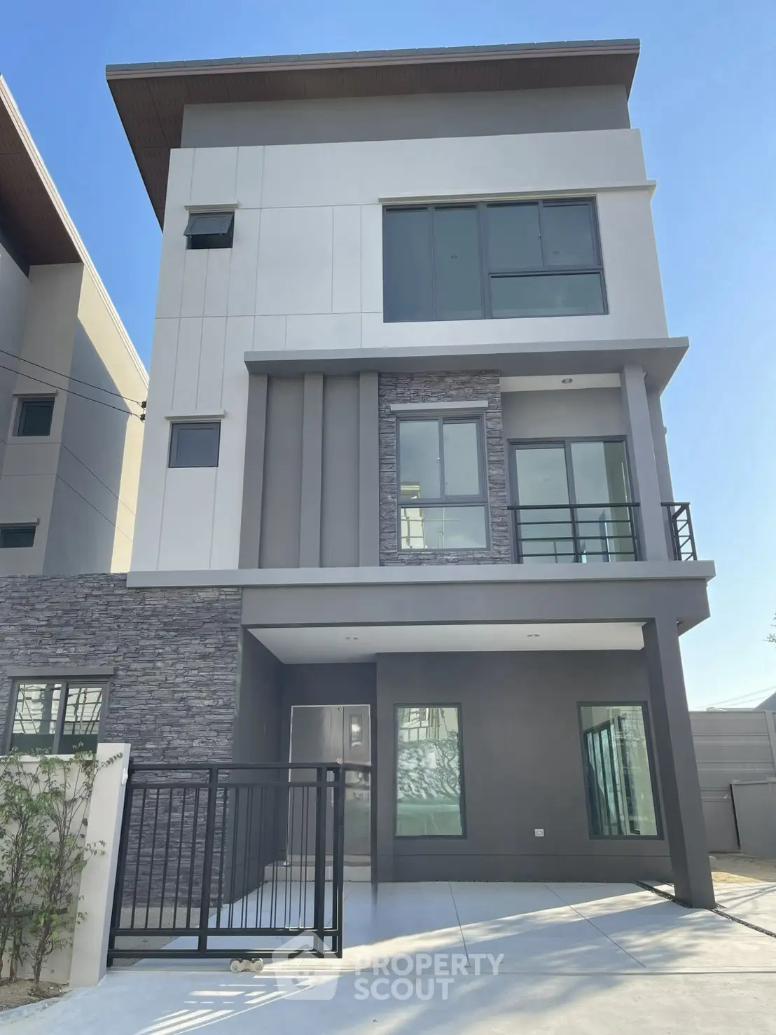 Modern three-story house with sleek design and large windows in a suburban setting.