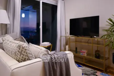 Modern living room with cozy sofa, stylish decor, and large TV near balcony view.