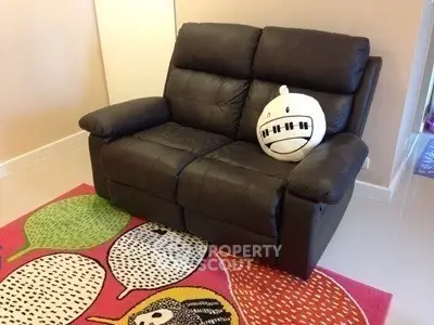 Cozy living room with stylish black leather sofa and colorful rug