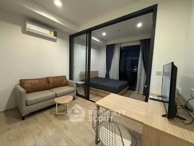 Modern studio apartment with cozy living area and bedroom, featuring stylish furniture and city view.