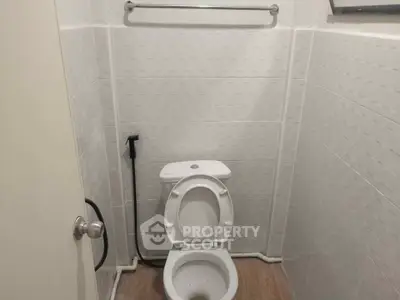Compact bathroom with white tiles and modern toilet design.