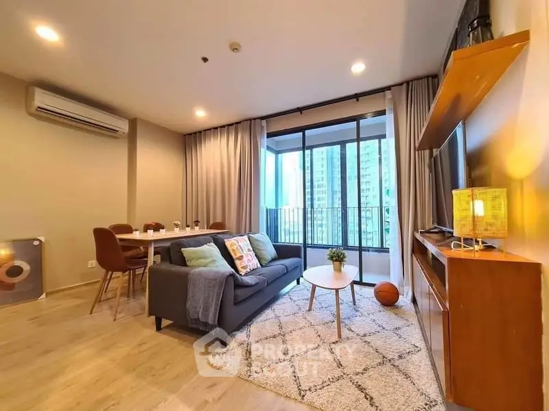 Modern living room with cozy decor and city view balcony in high-rise apartment.