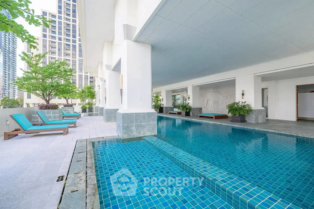 Luxurious modern pool area with stylish lounge chairs and lush greenery in a high-rise building.