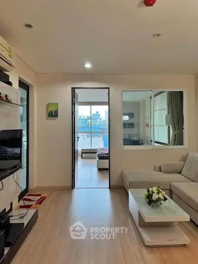 Modern living room with cozy sofa and view into bedroom, featuring sleek design and natural light.