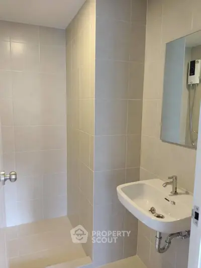 Modern bathroom with sleek sink and tiled shower area in a contemporary home.