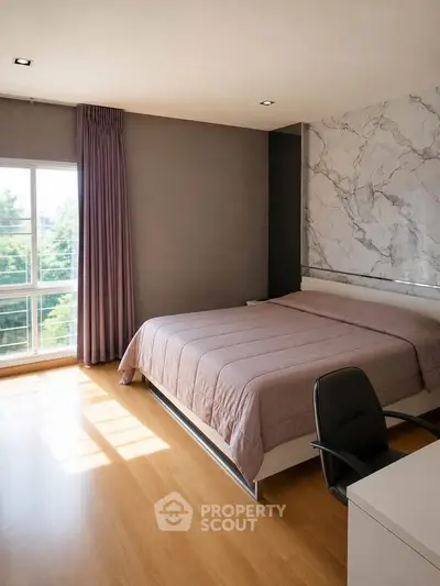 Spacious bedroom with large window and modern decor, featuring a comfortable bed and stylish chair.