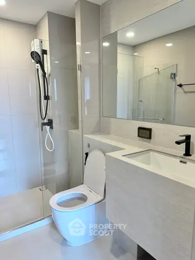 Modern bathroom with sleek fixtures and glass shower enclosure in a contemporary apartment.