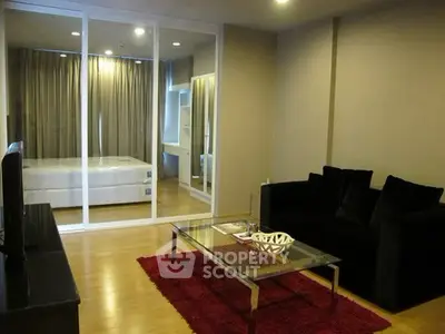 Modern living room with glass partition to bedroom, featuring sleek furniture and cozy ambiance.