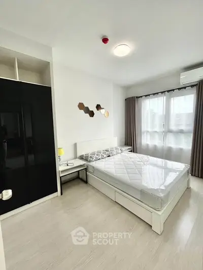 Modern bedroom with sleek black wardrobe and large window for natural light