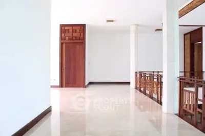 Spacious hallway with elegant wooden accents and polished floors in modern home.