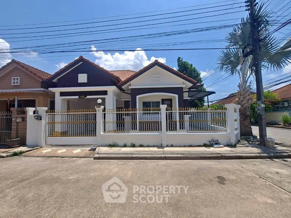 Charming suburban house with fenced yard and tiled roof under clear blue sky.