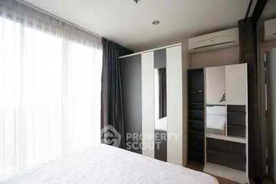 Modern bedroom with large window and stylish wardrobe in a bright apartment.