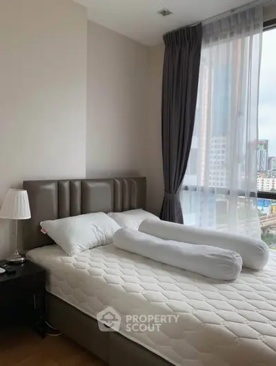 Modern bedroom with city view, featuring a stylish bed and elegant curtains.