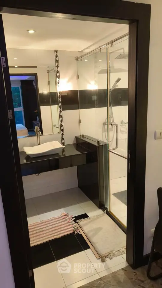 Modern bathroom with sleek black and white design, glass shower, and stylish fixtures.