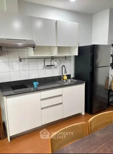 Modern kitchen with sleek cabinets and black appliances in a cozy apartment.