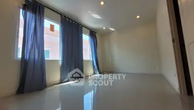Spacious and well-lit empty room with glossy tiled flooring, large windows draped with dark curtains, and a neutral color scheme ready for personalization.