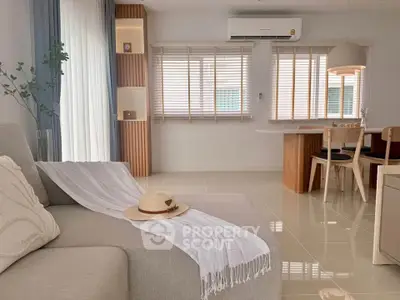 Modern living room with elegant decor and natural light, featuring a cozy sofa and stylish dining area.