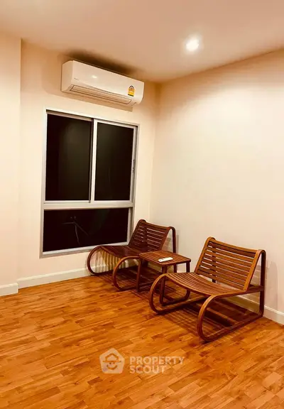 Cozy living room with wooden flooring and modern seating, featuring a sleek air conditioning unit.