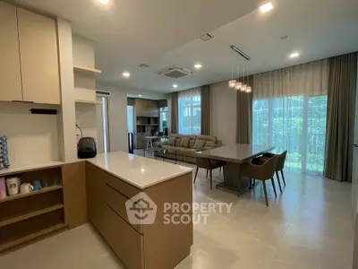 Spacious modern open-plan kitchen and living room with elegant furnishings and large windows.