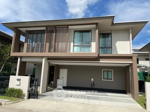 Modern two-story house with large windows and carport in a suburban neighborhood.