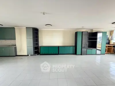 Spacious open-plan living area with built-in cabinets and large windows offering city views.